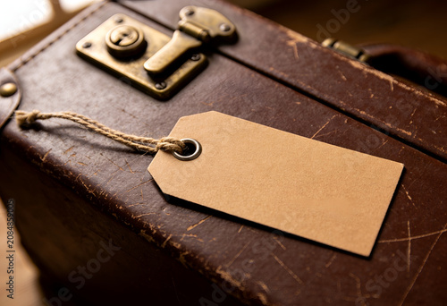 Vintage brown leather suitcase with blank luggage tag and brass hardware