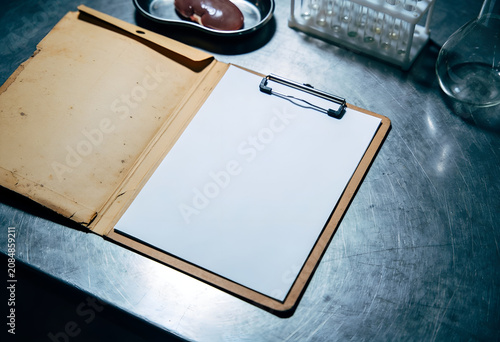 Clipboard with blank paper on metal table in laboratory setting