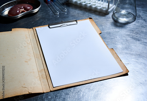 Clipboard with blank paper on metal table with medical equipment