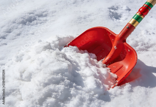 Red snow shovel scooping white snow on a winter day outdoors