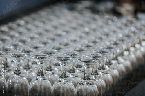 Foto Rows of clear glass wine glasses arranged neatly on a table, reflecting light an