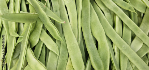 Tableau sur toile Close up of fresh flat green beans stacked in a market display, showing natural texture, overlapping pods and abundant fresh produce for grocery and vegetable retail