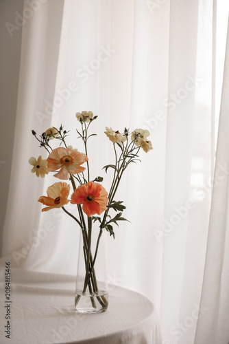 Bright ranunculus bouquet in glass vase with window light
