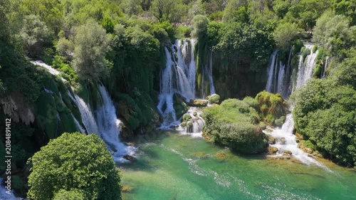Aerial drone panorama of spectacular cascading waterfalls surrounded by lush green forest and clear river
