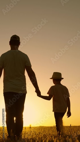 Kid father walks through meadow sunset. Dad, little son. Parent dad, child boy walking together outdoors. Happy family, travel, sunset. Family education. Dad little son walk outdoors sun rays, field