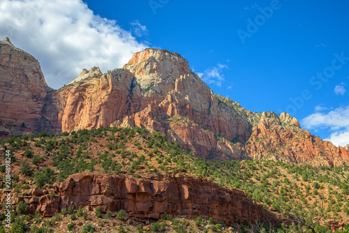 Foto Layered red rock formations towering above pine-dotted slopes and canyon cliffs