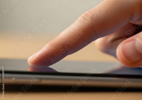 A close up view of a person's finger gently touching and interacting with a smartphone screen, indicating digital use.