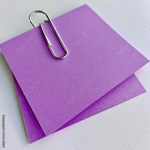 Two purple paper notes held together by a metal clip