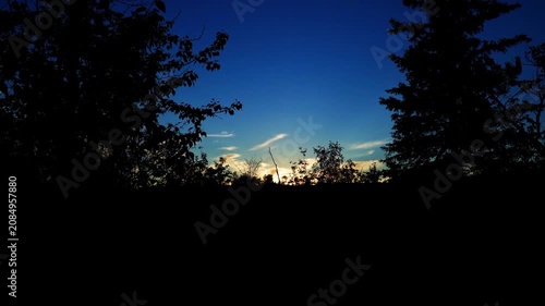 Distant views of spectacular colorful clouds illuminated by the last rays of the setting sun. Rich golden, orange, pink, and deep blue tones create a dramatic summer evening sky.