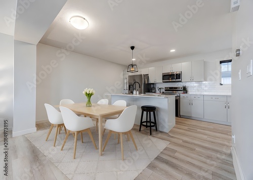 Bright open plan kitchen and dining space with white cabinetry and wooden floors interior residential architecture furniture contemporary spacious lifestyle minimalist
