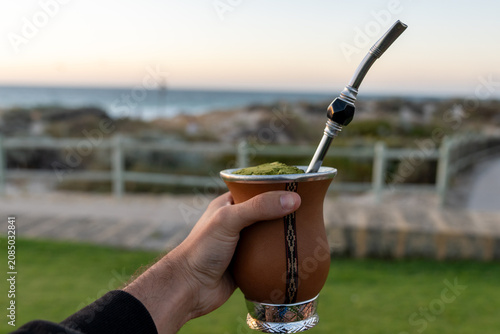 фотографія Hand holding yerba mate gourd on a beach