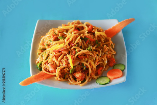 Spicy Stir Fried Noodles with Egg and Vegetables on Blue Background