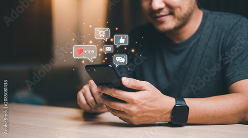 A man using a smartphone with floating social media notification icons representing digital engagement and online connectivity