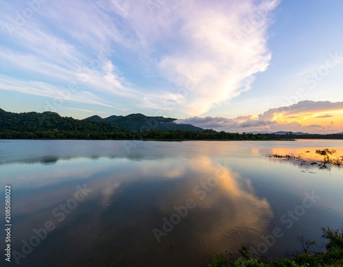 Background image of the reservoir. Beautiful sunrise or sunset sky over calm lake with reflection in surface water in the morning or evening. copy space. Lam Taphen Reservoir, Suphanburi.