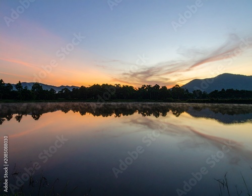 Background image of the reservoir. Beautiful sunrise or sunset sky over calm lake with reflection in surface water in the morning or evening. copy space. Lam Taphen Reservoir, Suphanburi.