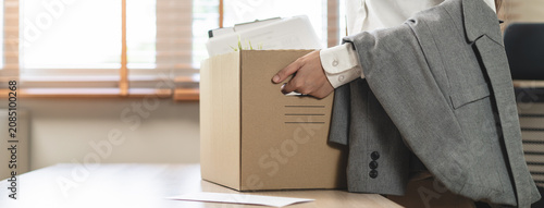 Close-up of a businessman holding a cardboard box with personal belongings after resignation.