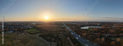 Aerial view of Hanover Langenhagen Silbersee at sunset, featuring the surrounding forest, urban landscape, and a highway in Hanover, Lower Saxony, Germany.