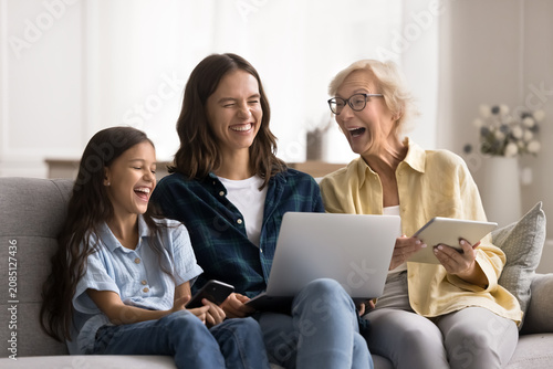 Tableau sur toile Joyful multiple generation family women using wireless devices, hold digital tab