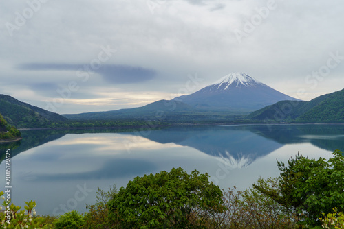 Spectacular spring landscape of Mount Fuji and its mirror reflection with a huge lenticular cloud (Tsurushi-gumo) over Lake Motosu, Yamanashi, Japan.