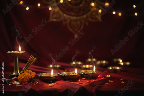 Diwali diya oil lamps on red fabric, traditional Indian festival celebration with incense and marigold flowers, glowing bokeh lights background