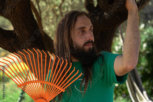 Man with long hair and beard holding rake