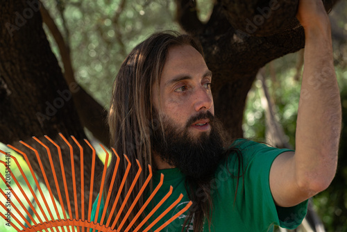 Man with beard holding rake working outdoors