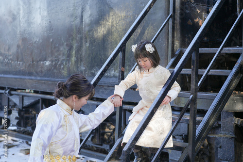 Fotografie Two women descend metal stairs beside a rusted train car