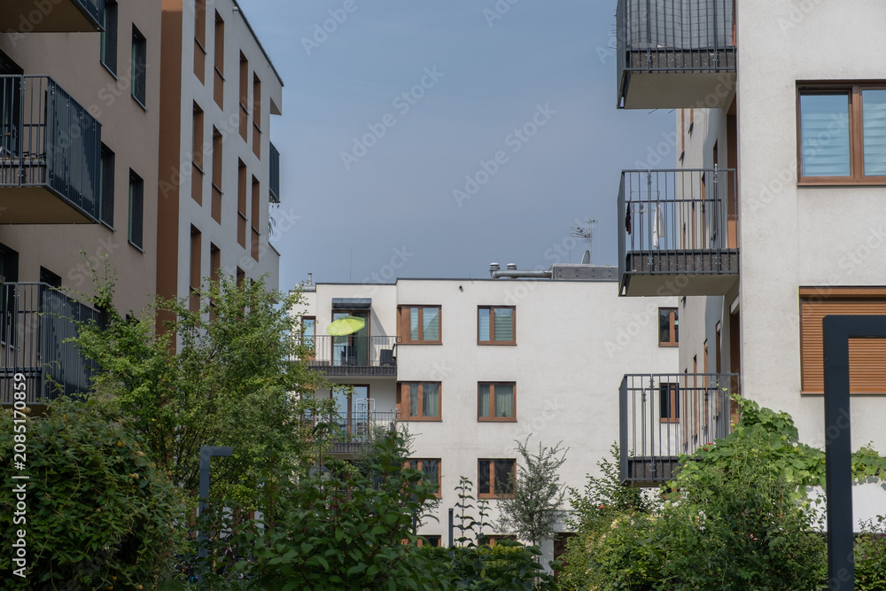 Fototapeta premium serene residential buildings with balconies and windows in an urban residential area at ground level featuring concrete, metal, and glass materials and greenery.