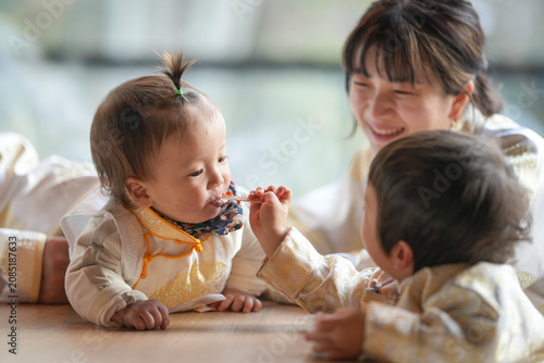 Soft light bathes a warm, wooden table. Two toddlers engage in joyful, playful sharing. One child offers a snack with bright, curious eyes. The other smiles, eyes sparkling with delight