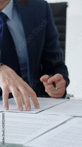 Foto Professional businessman's hands reviewing multiple legal documents spread on a clean office desk