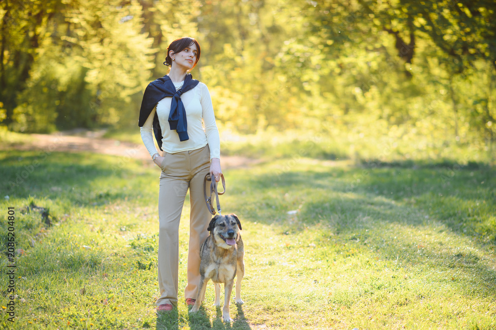 Fototapeta premium Woman and dog enjoying a walk in nature park