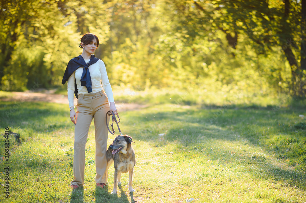 Fototapeta premium Woman and dog enjoying a walk in park