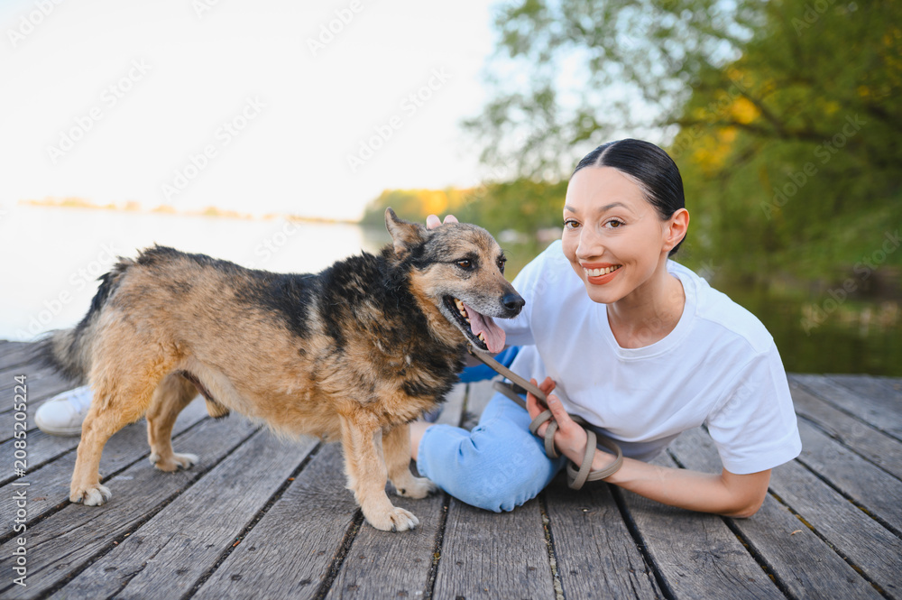 Fototapeta premium Woman smiling, petting dog on wooden pier