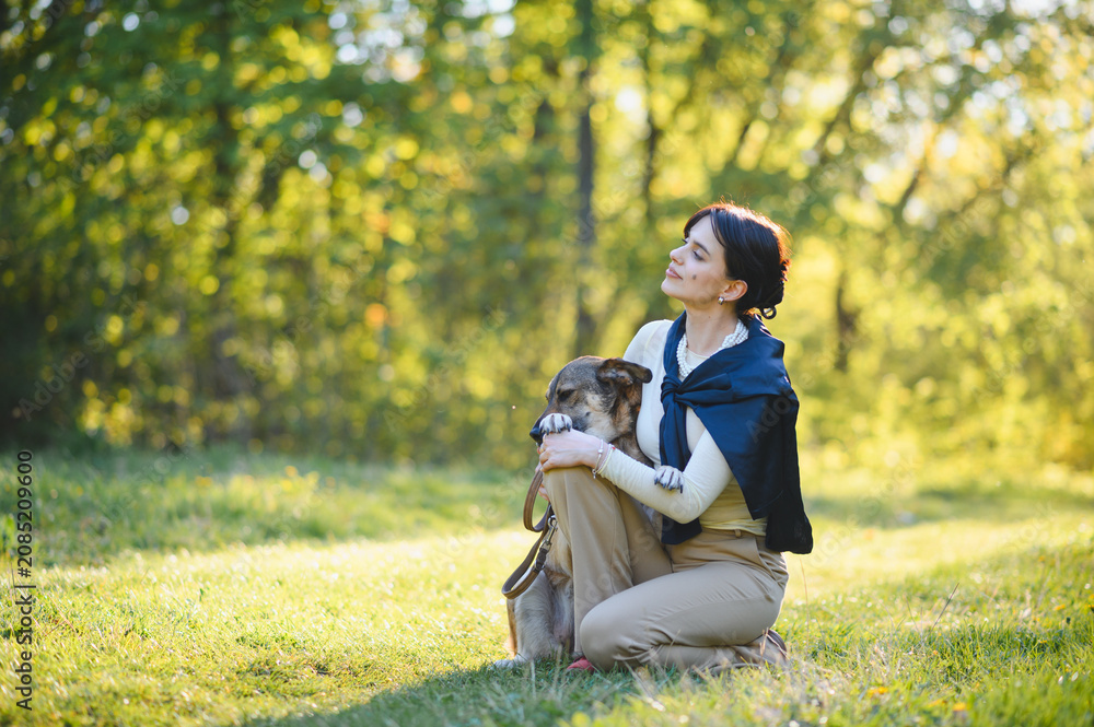 Fototapeta premium Woman petting dog relaxing in sunny park