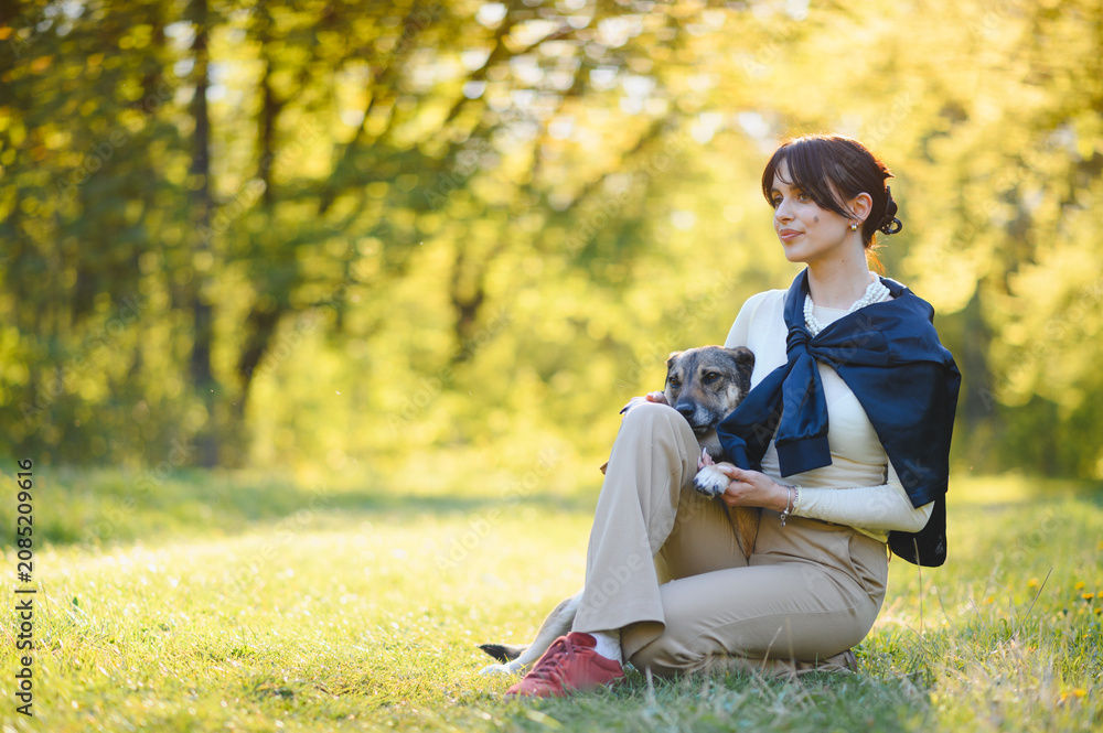 Fototapeta premium Woman relaxing with dog in sunny park