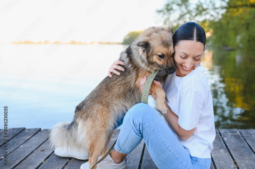 Fototapeta premium Woman hugging pet dog bonding by lake