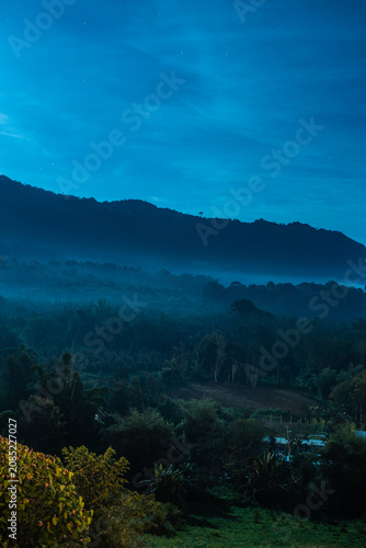 Mountain range at night with foggy forest.