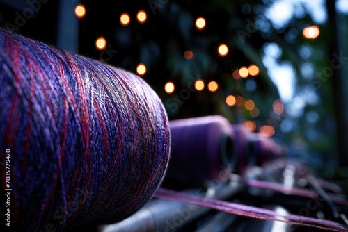 Close-up of purple spools of yarn with warm lights in soft focus background