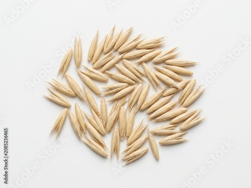 A pile of raw oat grains scattered on a surface isolated on white background