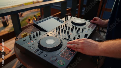 focused dj hands mixing music in a professional booth overhead view with plastic and wood materials and gray and black colors, commercial natural light and clean background.