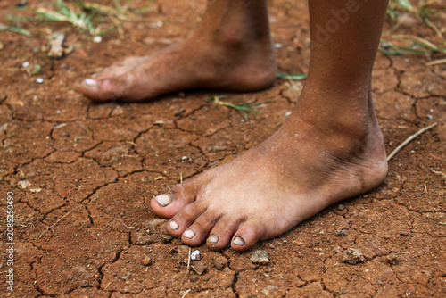 Fotografie The bare feet of a small child stood on the surface of the ground which was very
