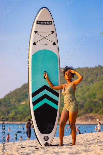 Woman Standing with Paddleboard on Sunny Beach