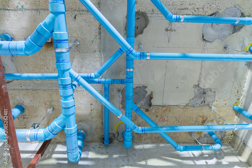 Blue PVC plumbing pipes in concrete wall installation