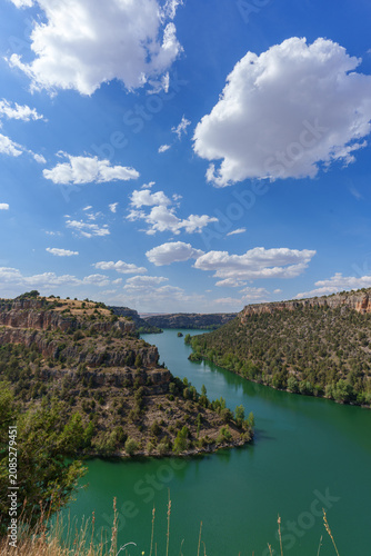 Duraton river flowing through hoces canyon with green water and steep rocky cliffs under blue sky