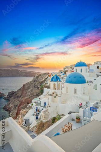 Fotografie Gorgeous Santorini blue dome churches, vertical sunset, whitewashed Oia, Aegean Sea Greece