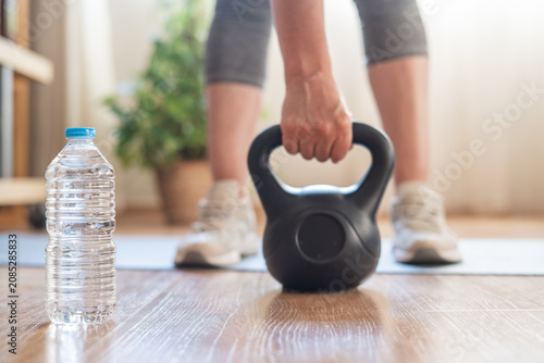 Cuadro en lienzo Person's hand gripping a kettlebell ready for a strength workout on the floor at