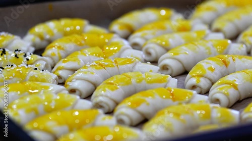 Hands Sprinkling Sesame Seeds and Spices on Homemade Bread Rolls in Baking Tray Before Baking