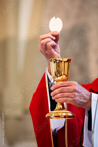 Konstfotografi Catholic priest elevating the Eucharistic host above golden chalice during Holy