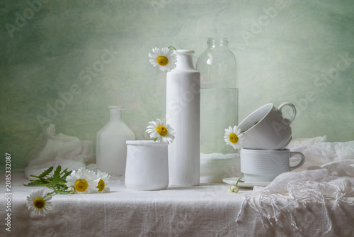 Tableau sur toile Contemporary still life with daisies and white dishes on a light background