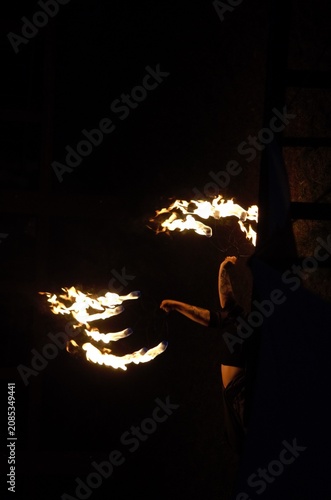 Obraz na plátně Fire Show performer spinning burning poi at night on dark background
